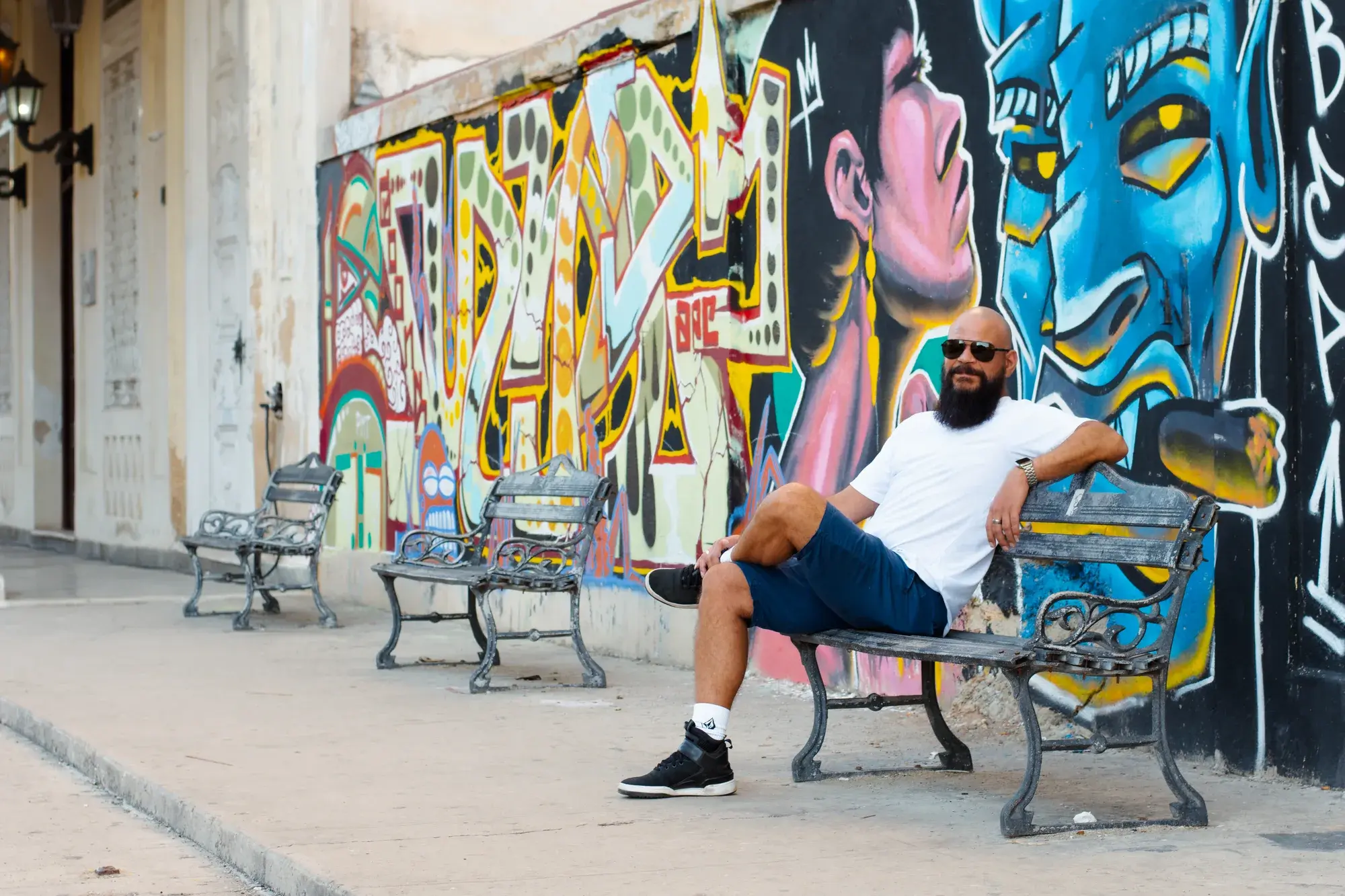 Sentado frente a un mural de colores en La Habana