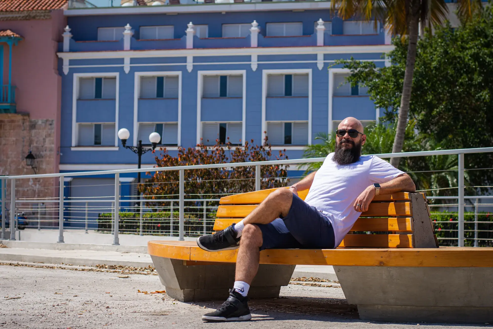 Sentado en un banco frente a una fachada azul de La Habana